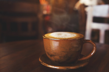 cup of hot coffee on table in cafe with morning light - vintage and dark color tone styles