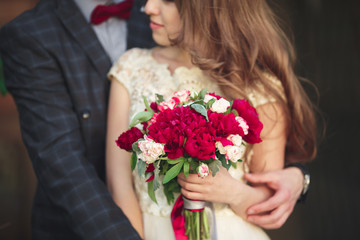 Wedding couple hugging, the bride holding a bouquet of flowers in her hand, groom embracing
