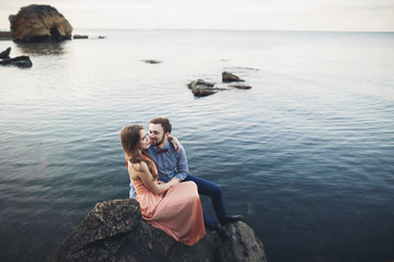 Wedding couple kissing and hugging on rocks near blue sea