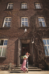Fototapeta na wymiar Young wedding couple in love story, bride and groom posing near building on the background. Krakow