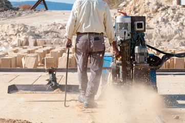 Worker using a vertical sawing machine to carve the stone in a tufa quarry