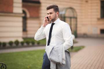 Stylish young businessman talking on the phone outdoors