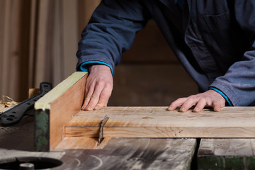 Carpenter's hands cutting wood board with Table Saw