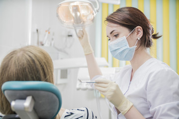 beautiful female dentist doctor, young woman doctor in a dental clinic. the dentist sits in the Cabinet beside the chair with the patient