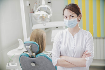 beautiful female dentist doctor, young woman doctor in a dental clinic. the dentist sits in the Cabinet beside the chair with the patient