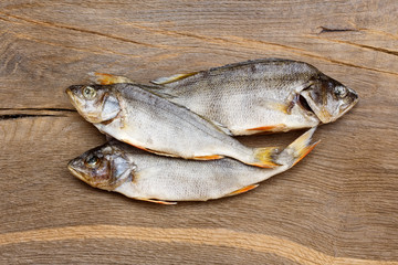 Three dried fishes on a wooden table.