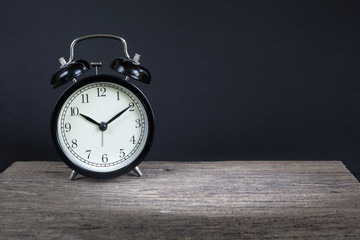Naklejka premium Alarm clock on wood with a black background