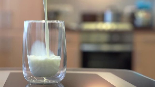 Pouring milk into a glass in the kitchen, shallow focus