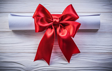 Paper roll with red bow on wooden board holidays concept