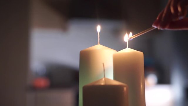 Girl hand lighting up three candles