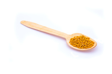 Mustard seeds in wooden spoon isolated on white