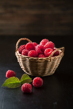 Ripe fresh raspberries with leaves in a basket