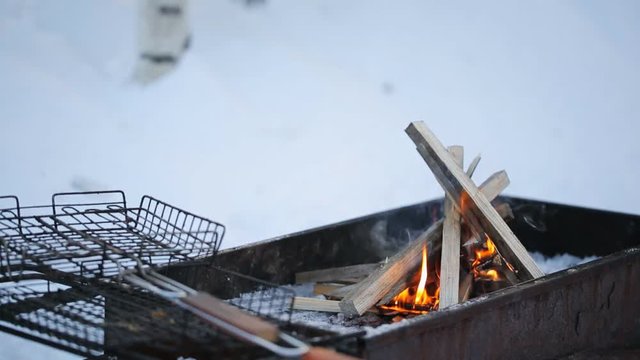 Close to grating lying on a brazier burning flames on a background of snow and birch.