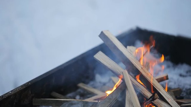 Flames fire eats timber in a brazier standing outside winter.