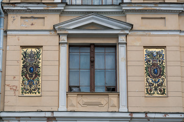 Fragment of classic building wall. Window with a portico and a golden mosaic.