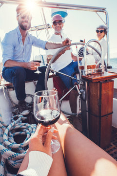Woman having red wine on the boat with friends in background