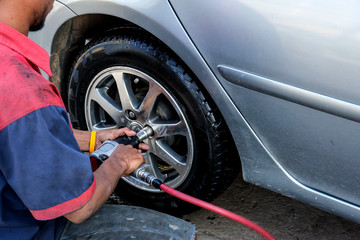 Auto mechanic changing a car tire in garage