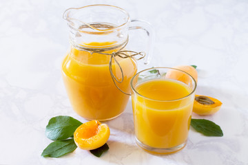 Naklejka na ściany i meble A refreshing summer drink with peach in a jug and glasses on a g