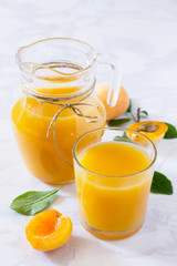 Naklejka na ściany i meble A refreshing summer drink with peach in a jug and glasses on a g