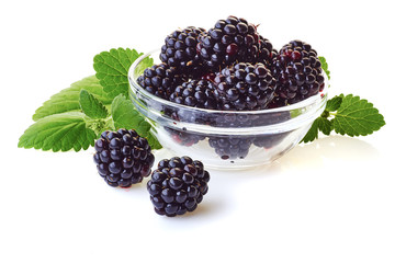 Glass bowl with blackberries and mint leaves on white