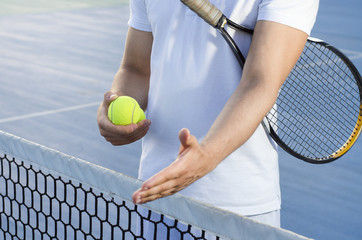 Male tennis player offering hand handshake on net, no face