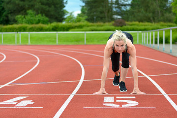 Athletic woman in the starter position on a track