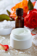 Obraz na płótnie Canvas Face cream with roses, bottle of aromatherapy essential oil and