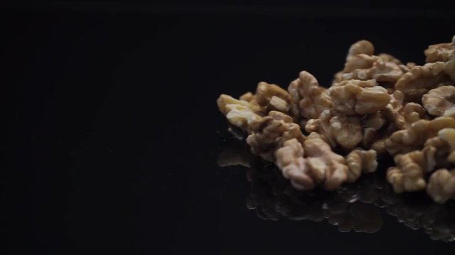 A pile of walnuts on a black reflecting table