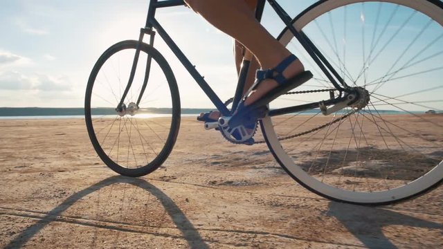 Close up shot of man riding vintage bike at the beach during sunset or sunrise, slow motion