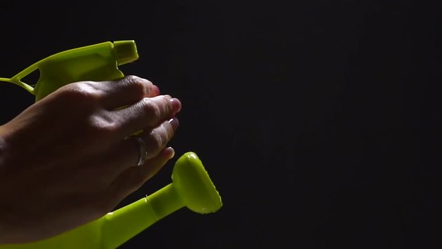 Green watering can with pulverizer and female hand, slow motion