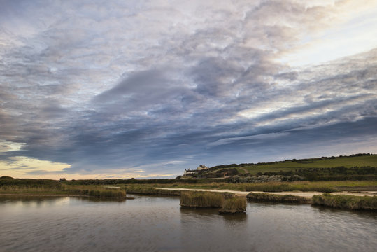 Landscape image of tidal pool at coast during evening with drama