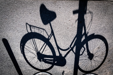Fototapeta na wymiar Ombra di una bicicletta da donna parcheggiata e legata a un palo