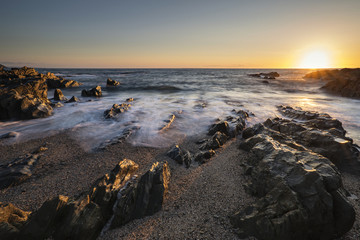 Beautiful vibrant sunset landscape image of calm sea against roc