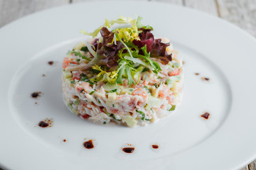 Salad from seafood on a white plate on a wooden table