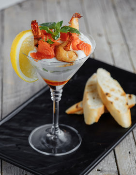 Salad Shrimp Cocktail Sauce With Salmon, Lemon And Basil On A Tray With Toast On A Wooden Table