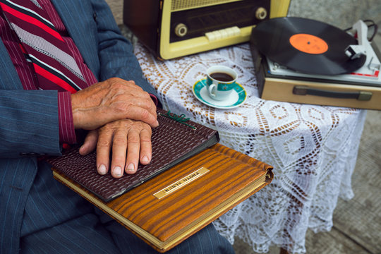 Senior man's hand touching an old photo album. Close up.