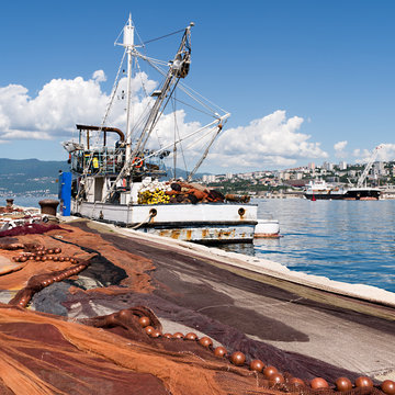 spread fishing nets, fishing boat on dock in port of Rijeka, Croatia
