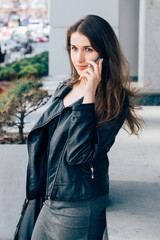 Young woman in leather jacket is talking on the phone 