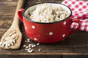 The red ceramic saucepan with white polka dots complete crumbly barley porridge