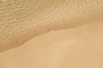 Beautiful crystal clear sea water, Gentle waves breaking on golden sand beach.  From above with copy space.