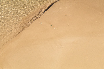 Beautiful crystal clear sea water, Gentle waves breaking on golden sand beach.  From above with copy space.