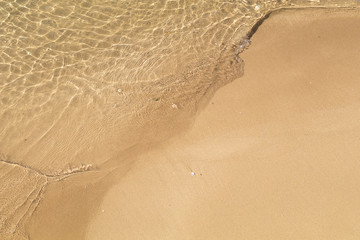 Beautiful crystal clear sea water, Gentle waves breaking on golden sand beach.  From above with...