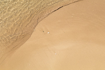 Beautiful crystal clear sea water, Gentle waves breaking on golden sand beach.  From above with copy space.
