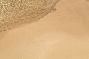 Beautiful crystal clear sea water, Gentle waves breaking on golden sand beach.  From above with copy space.