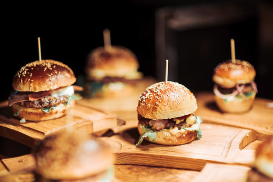 Gourmet Tasty Beef Burgers with Salad Slices on a Wooden Tray inside a bar waiting to be served