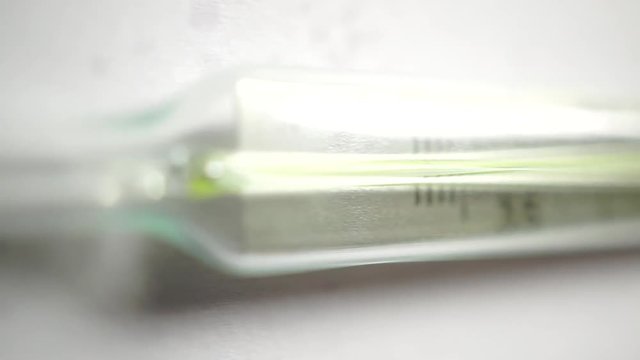 Macro dolly shot of medical thermometer on light background, shallow focus