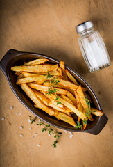 Potatoes fries in the bowl with salt and thyme