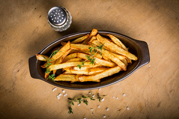 Potatoes fries in the bowl with salt and thyme