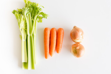 High angle view of celery, carrots and onions on a white table