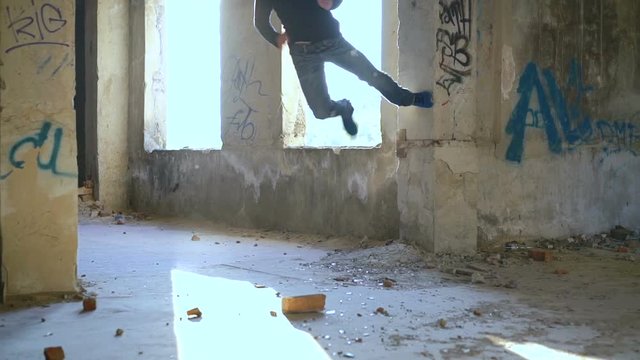 A free runner back flips off a wall of catacomb. Slowly